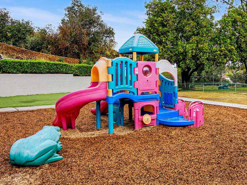 Colorful playground structure with slides on wood chip ground