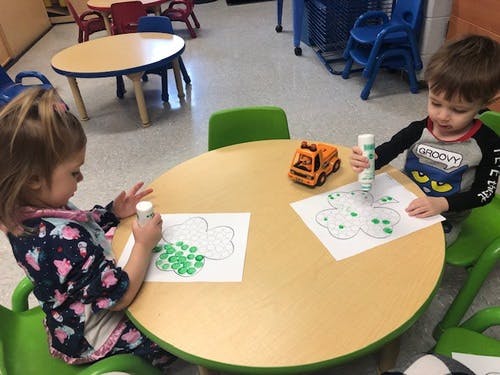 Two children sitting at a table doing an art activity