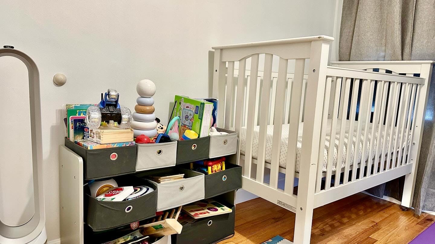Crib next to a storage unit with toys and books