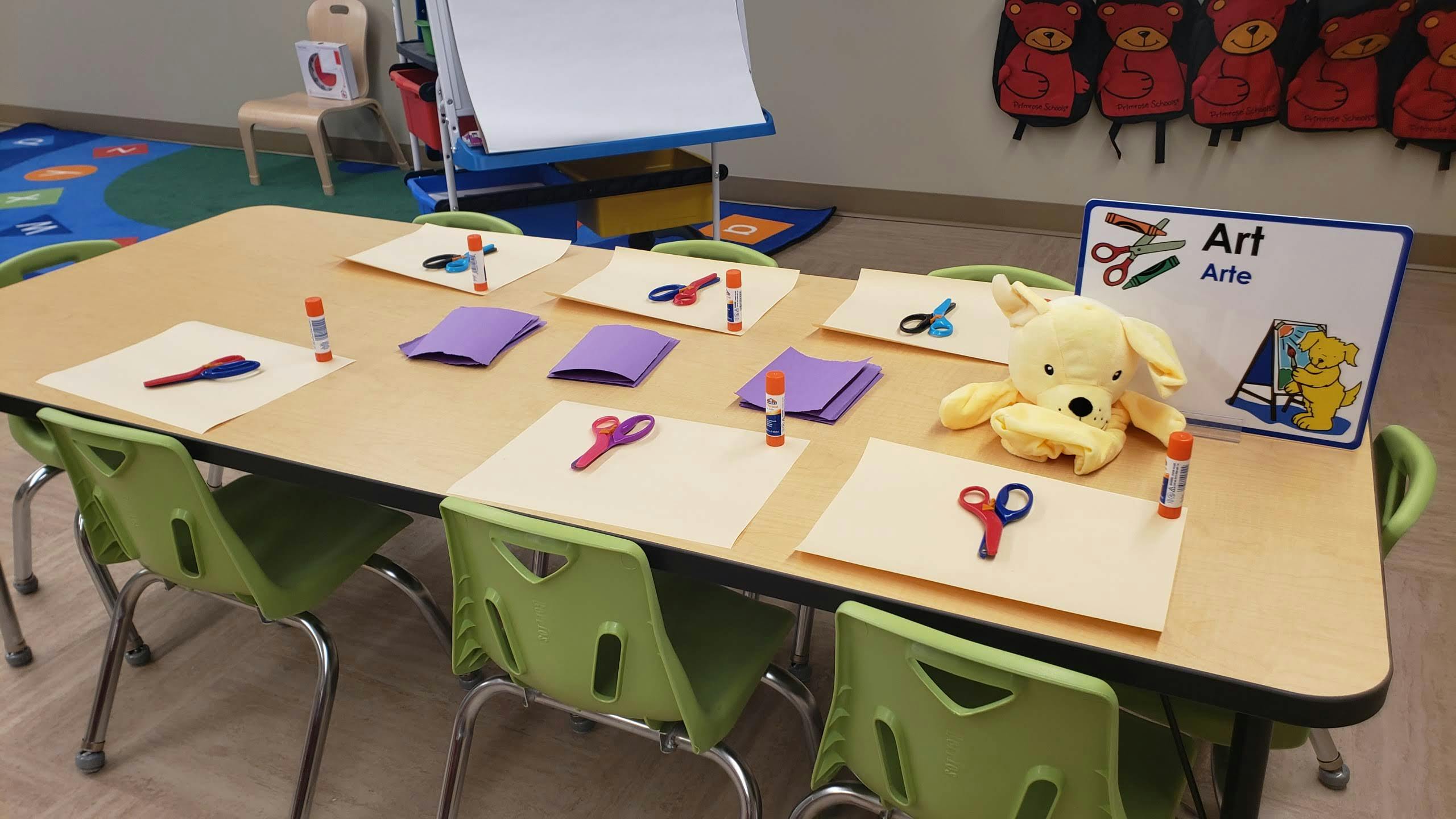 Classroom table with art supplies and a stuffed animal