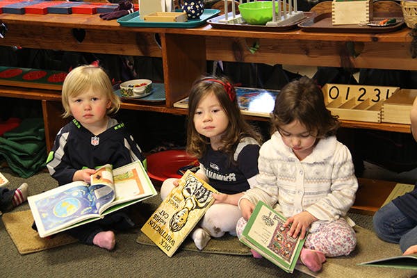 Three children sitting on the floor reading books