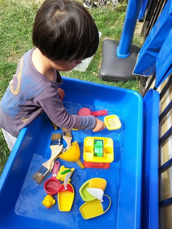 Child playing with toys in a blue water table