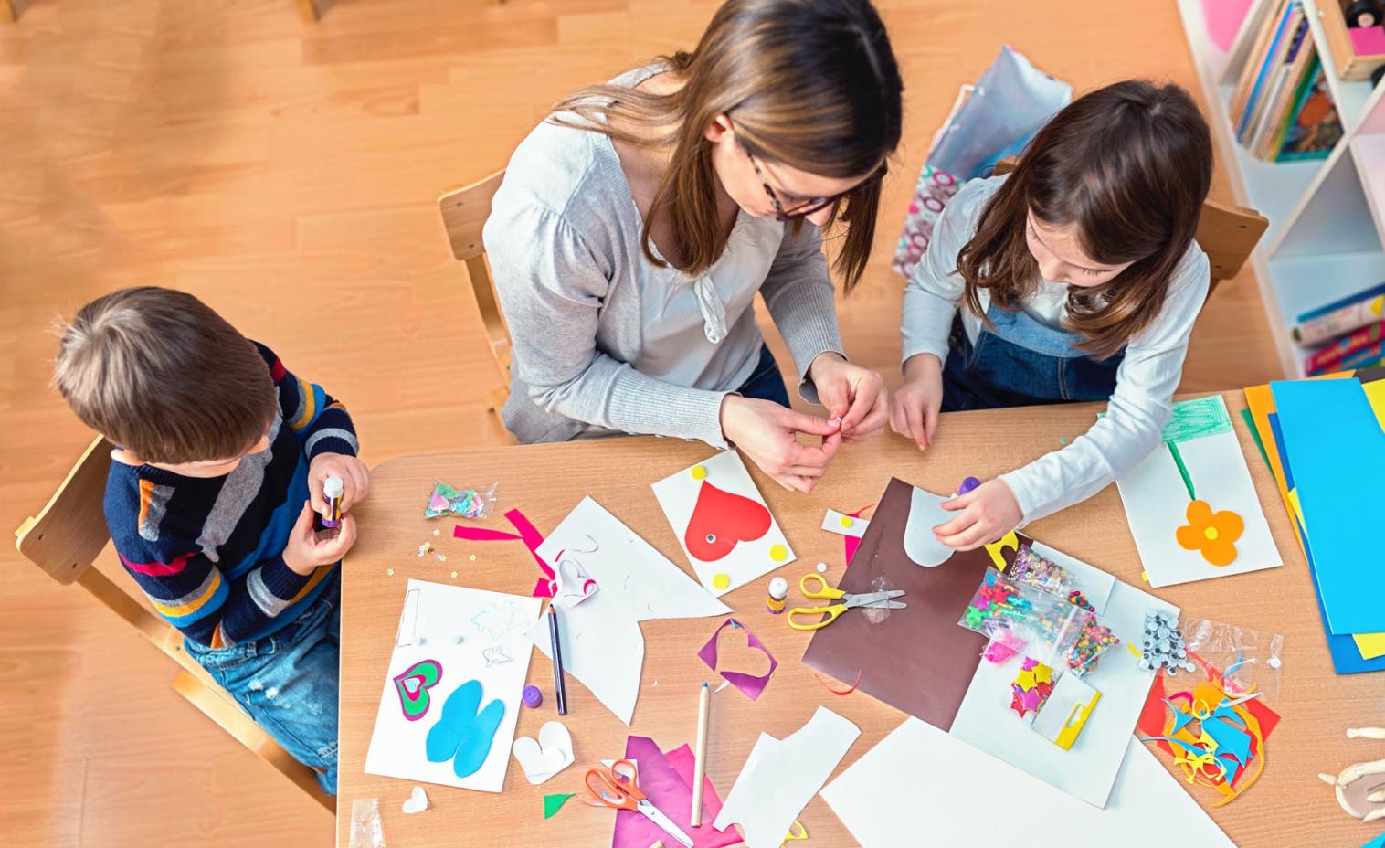 Adult and two children doing crafts at a table