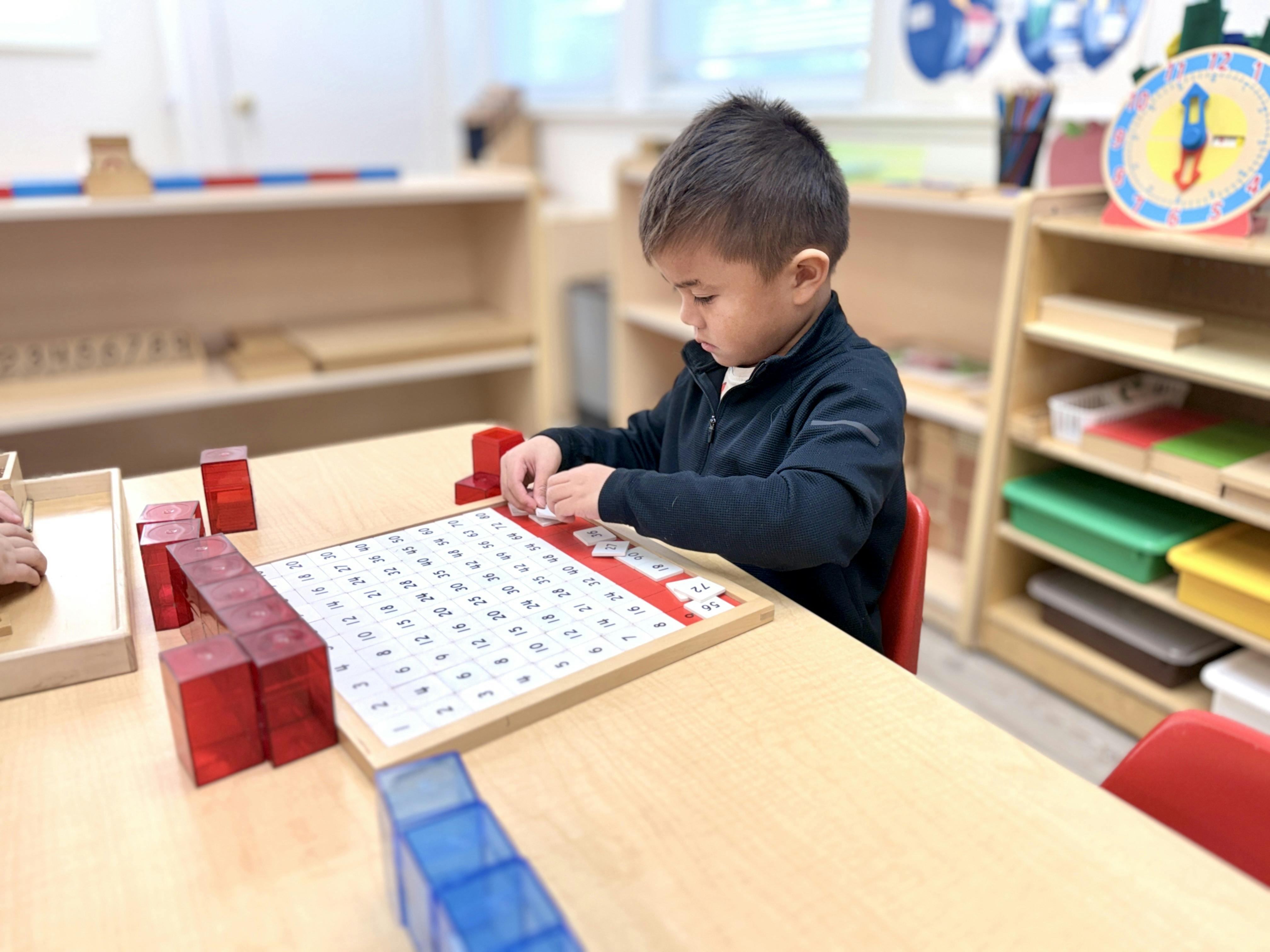 Child learning math with blocks and number boards in a classroom
