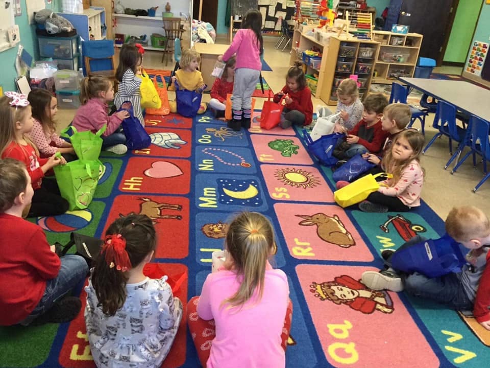 Children sitting on an alphabet rug in a classroom