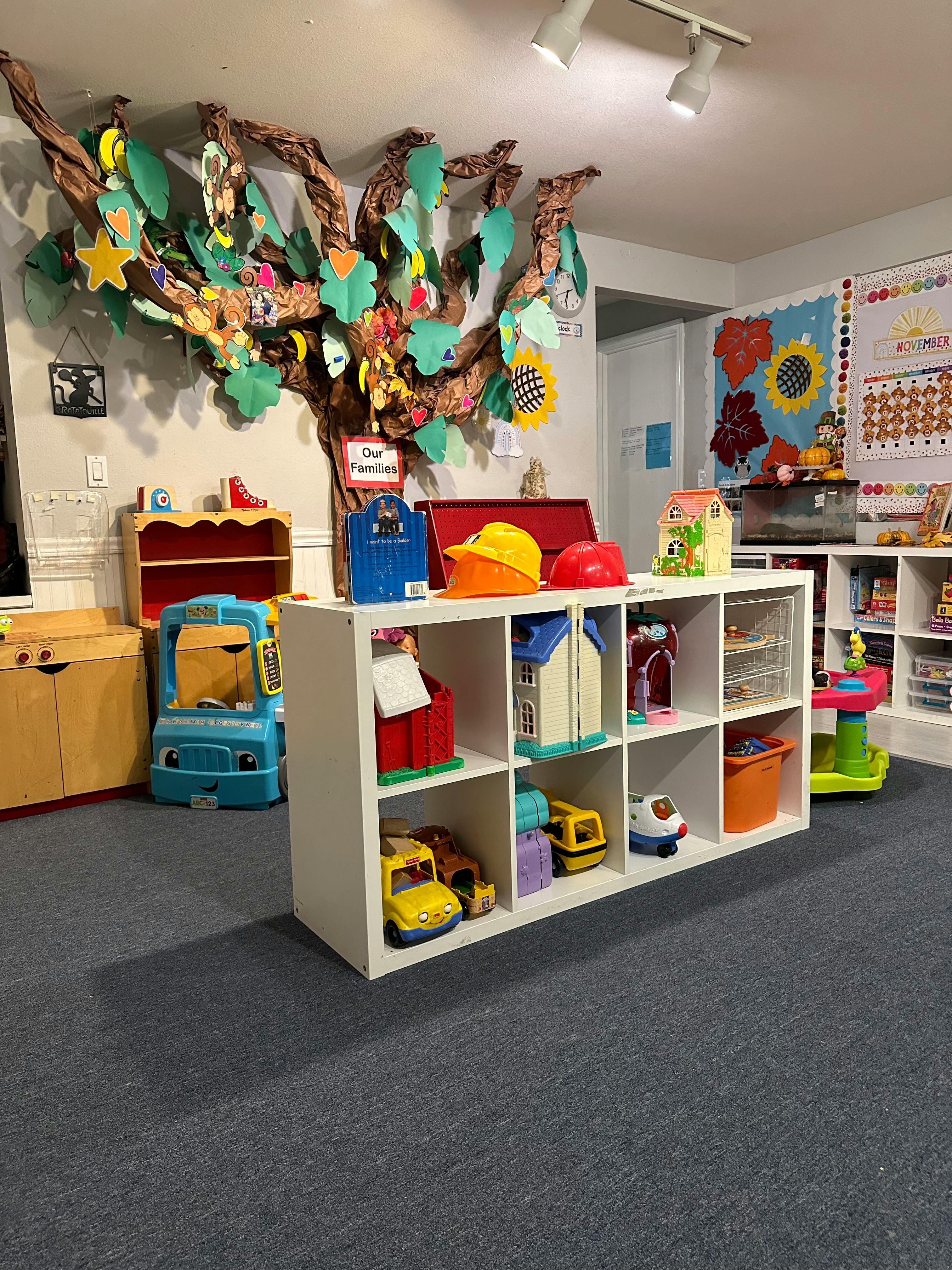 Classroom with a large tree decoration on the wall and toy storage shelves
