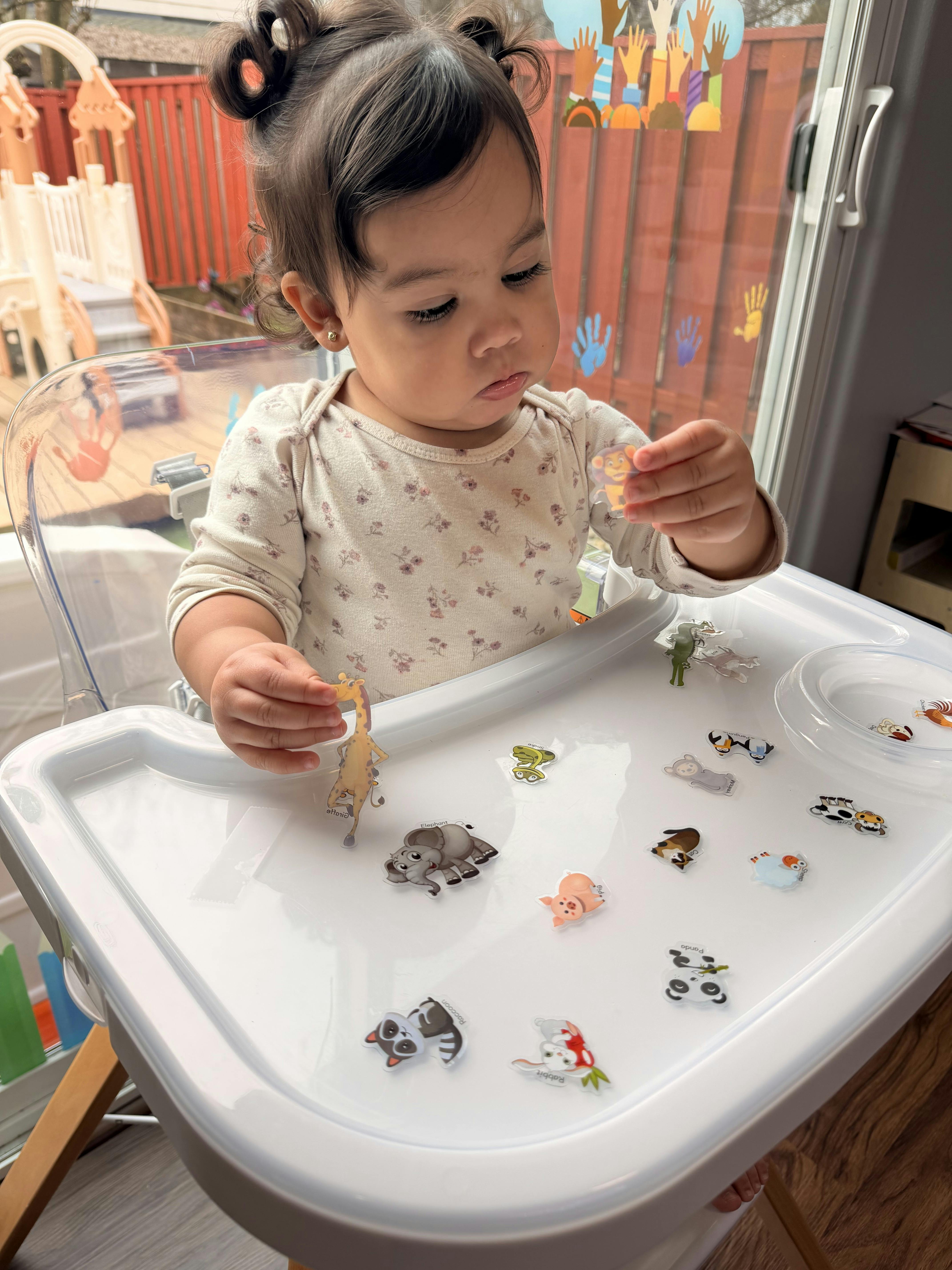 Child in a high chair playing with animal magnet toys