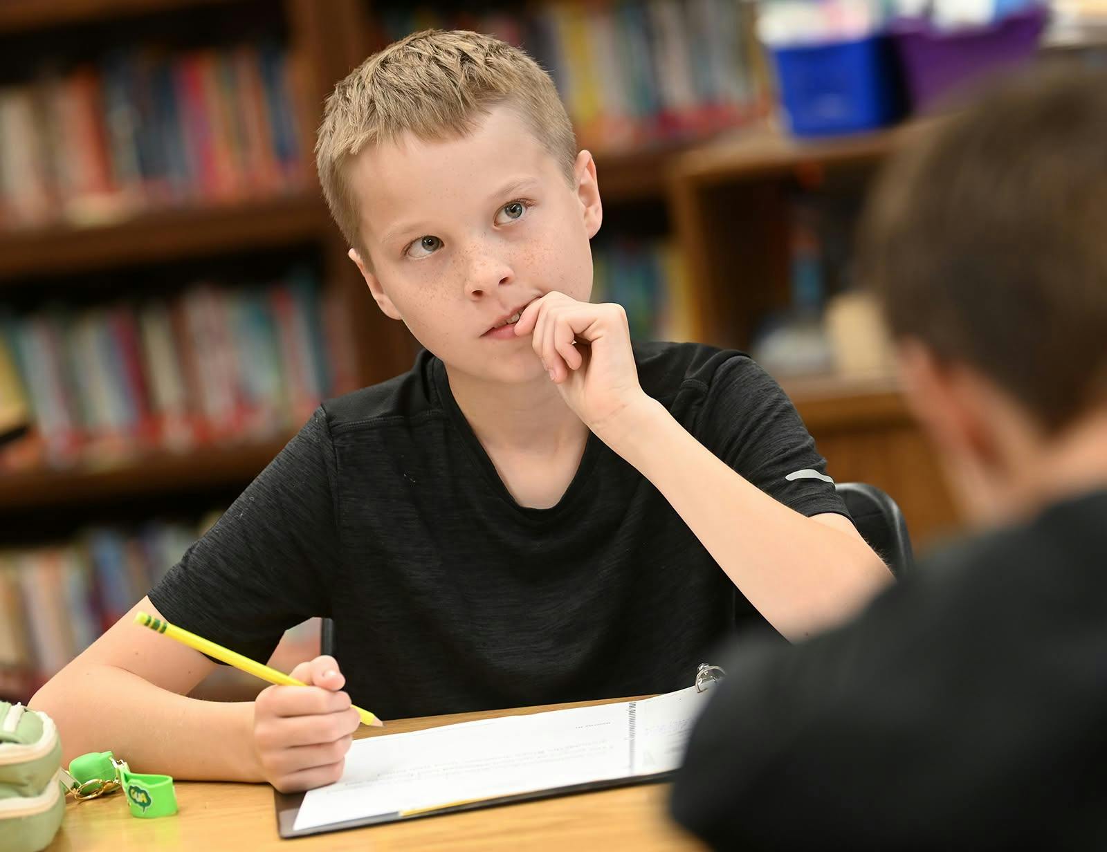 Child sitting at a desk with a pencil and paper