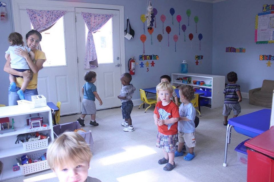 Adult holding a child in a room with other children