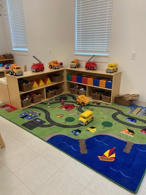 Playroom with toy trucks on shelves and a road-themed rug with toy vehicles