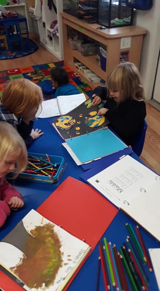 Three children at a table looking at papers and binders