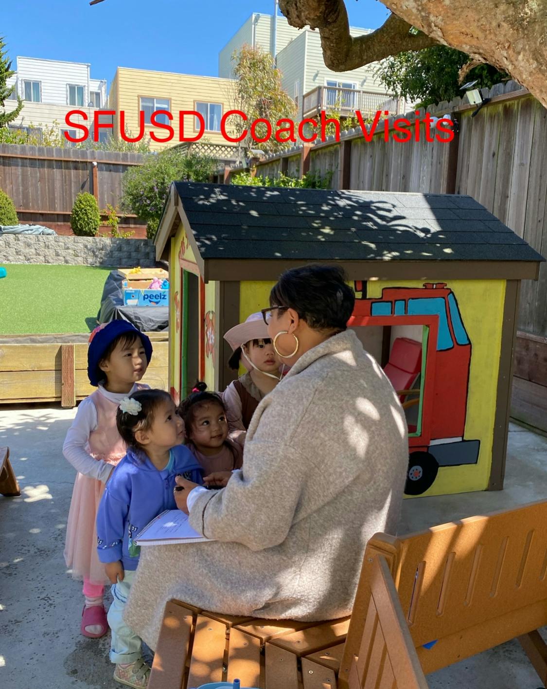 Adult sitting on a chair with children gathered around, SFUSD Coach Visits text