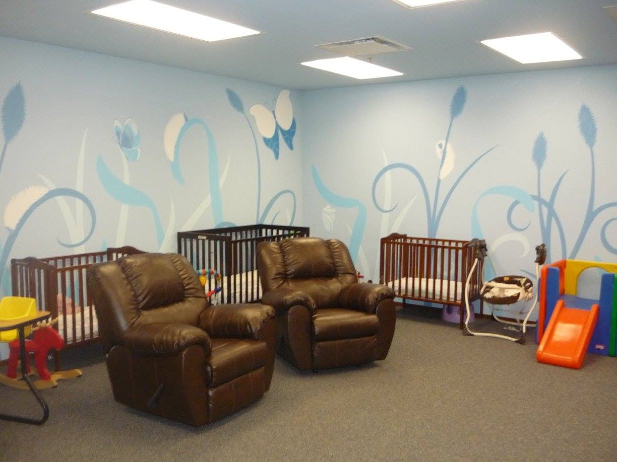 Nursery room with cribs, recliners, and play equipment
