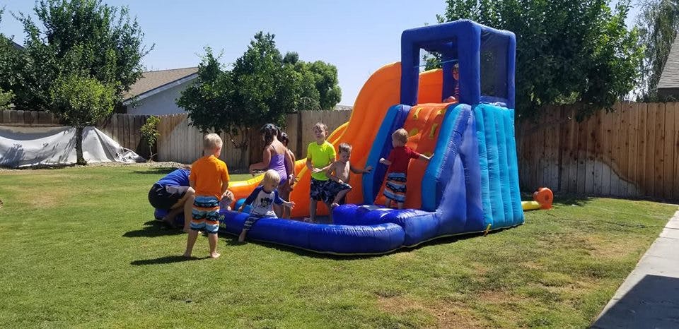 Children playing on an inflatable water slide in a grassy yard