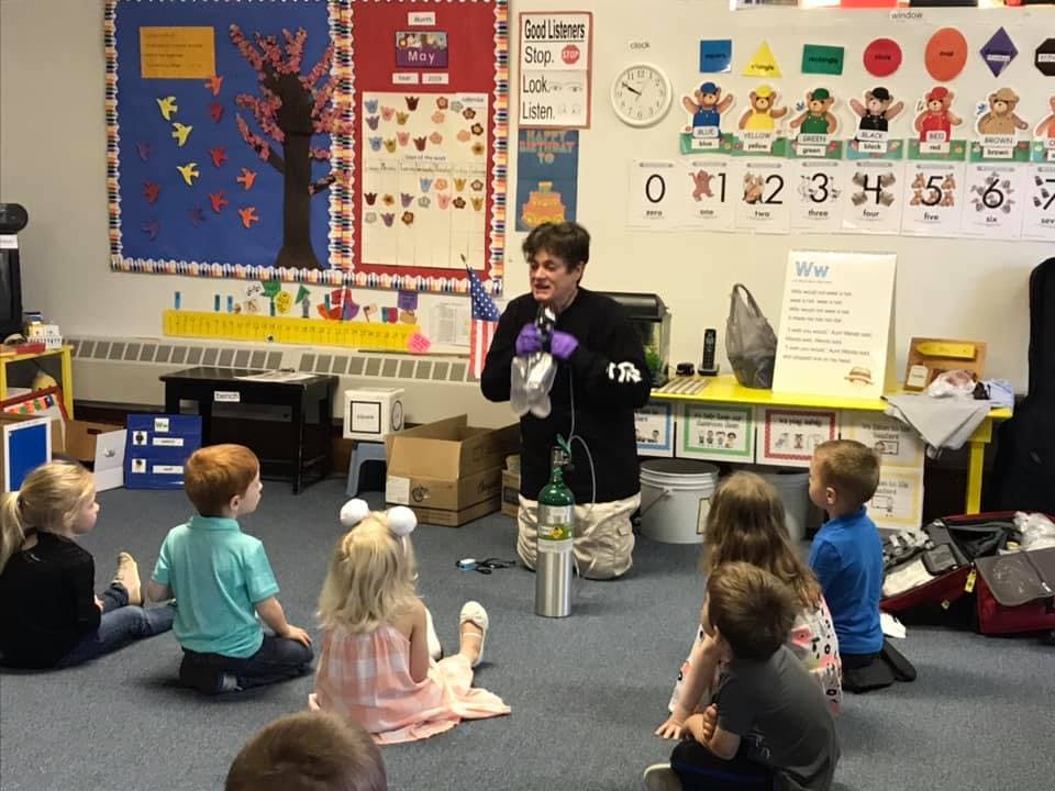 Person demonstrating science experiment to children in a classroom