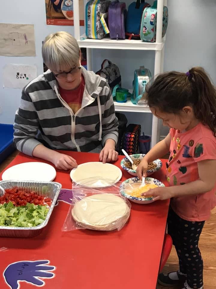 Person and child preparing food at a red table