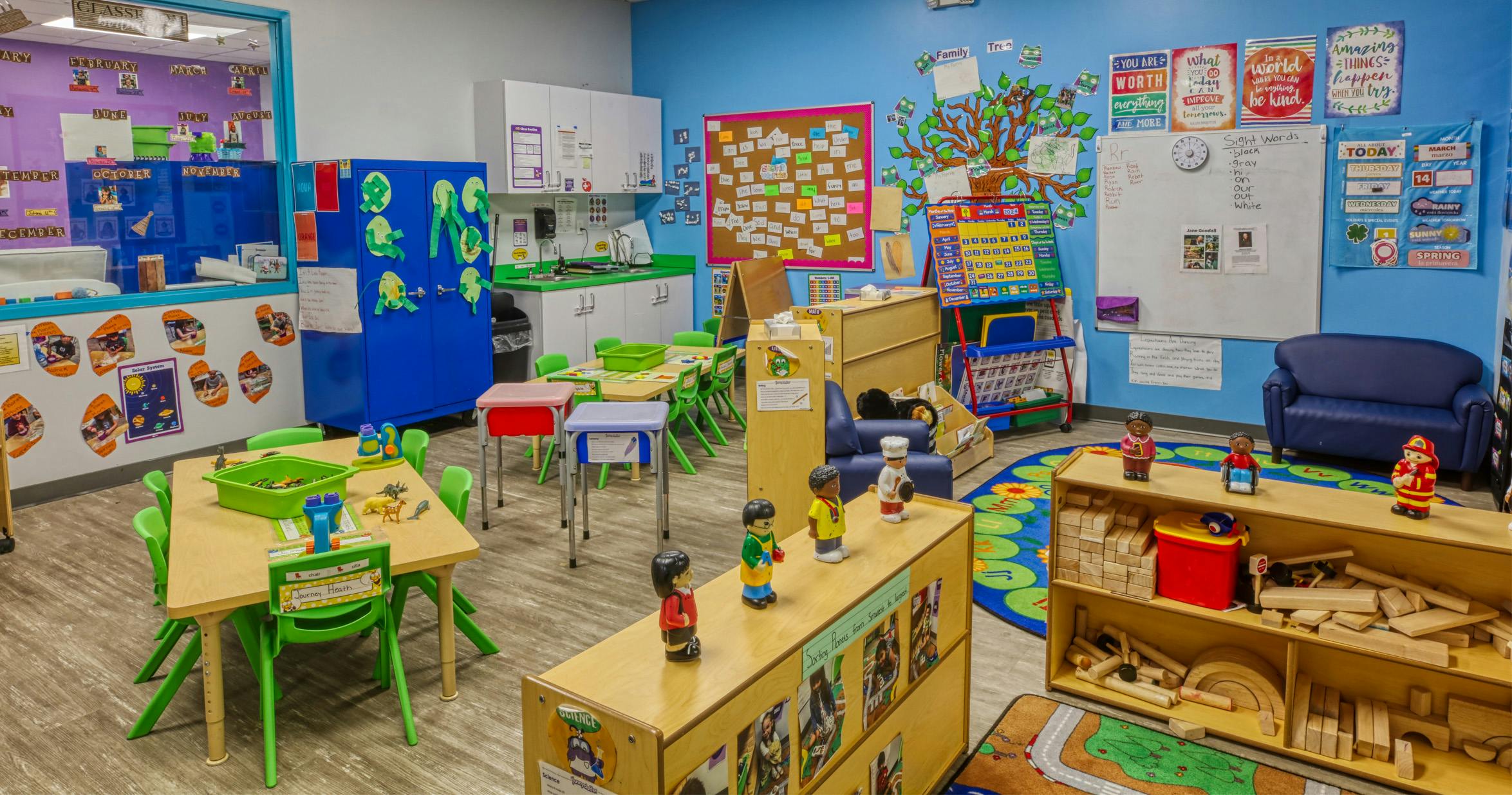 Colorful preschool classroom with tables, chairs, and learning decorations on the walls