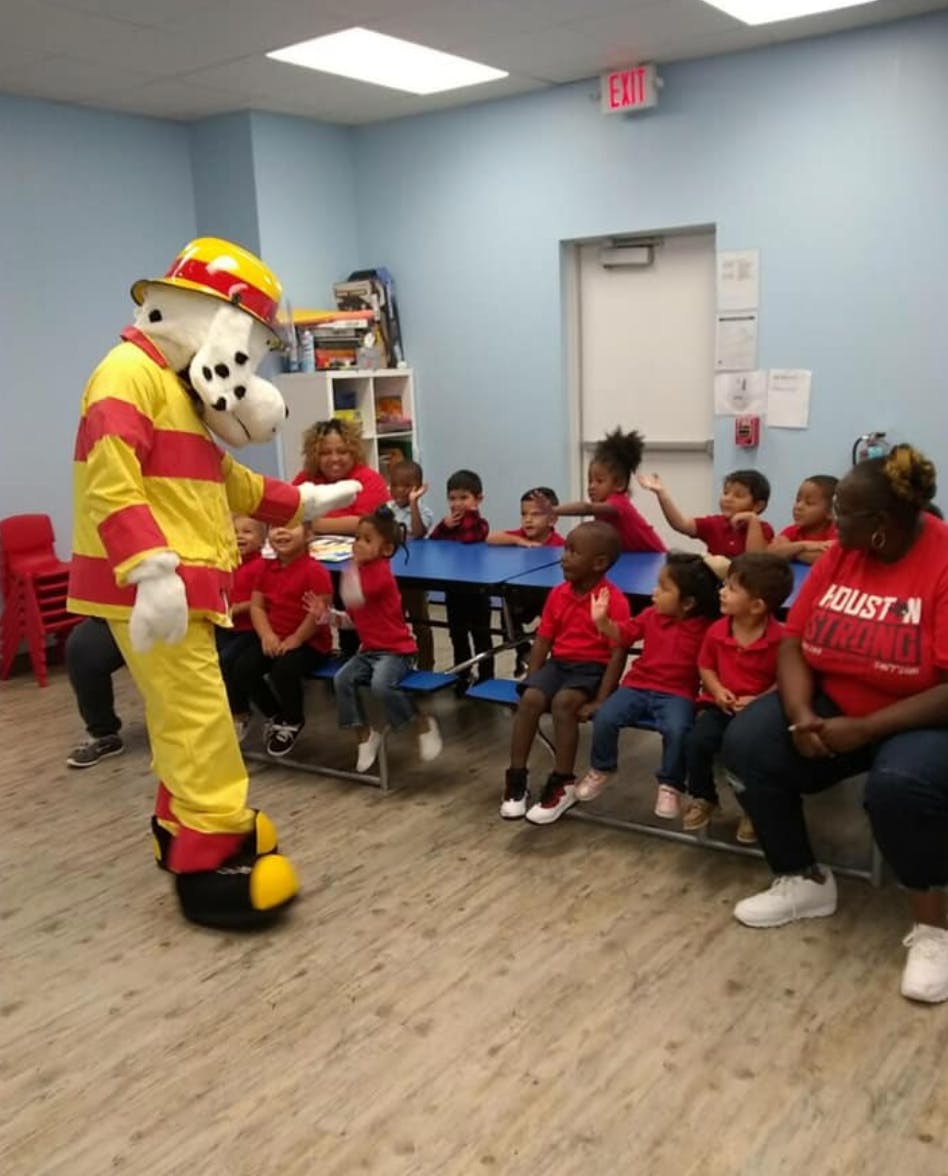 Mascot in firefighter uniform interacting with children in a classroom