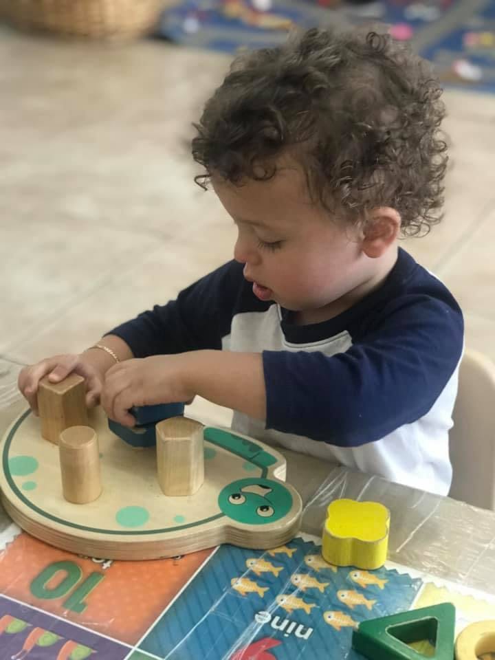 Child playing with a wooden shape sorter toy