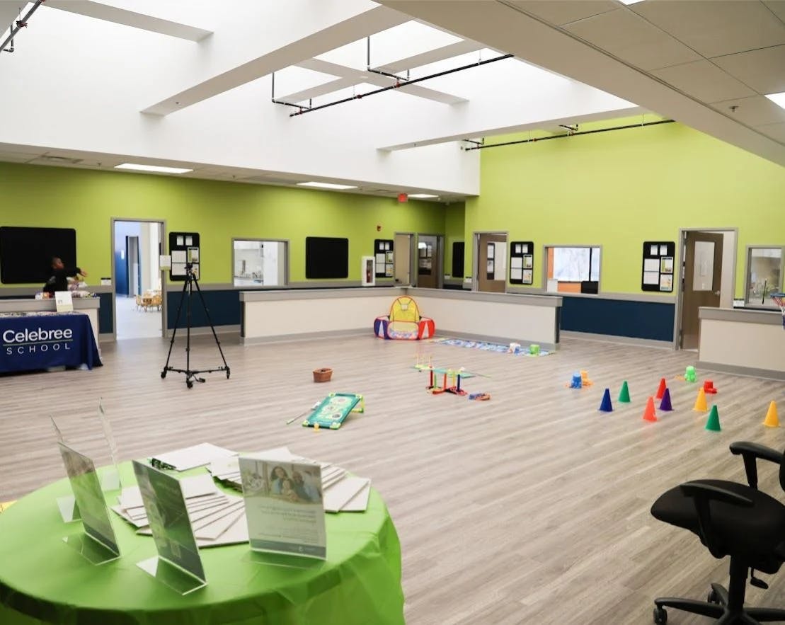Large room with light green walls and various play items on the floor