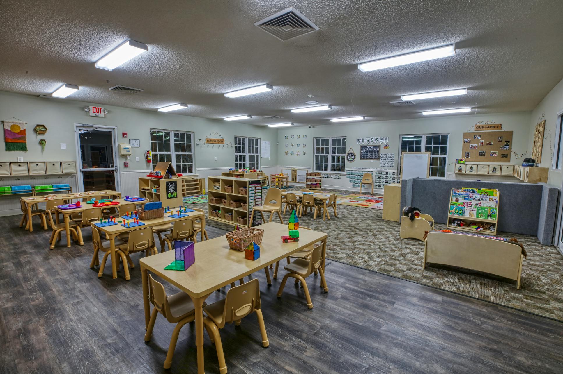 Classroom with multiple tables and chairs, shelves, and play areas