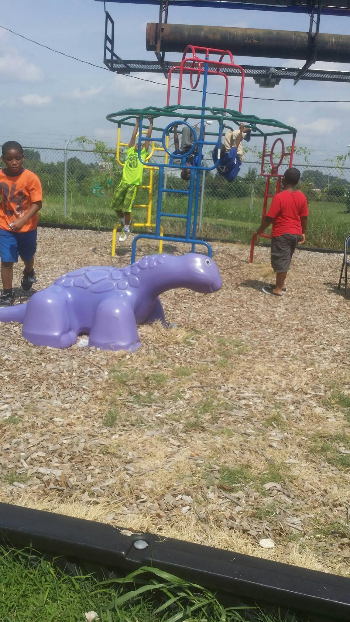 Children playing on a colorful playground structure with a purple dinosaur