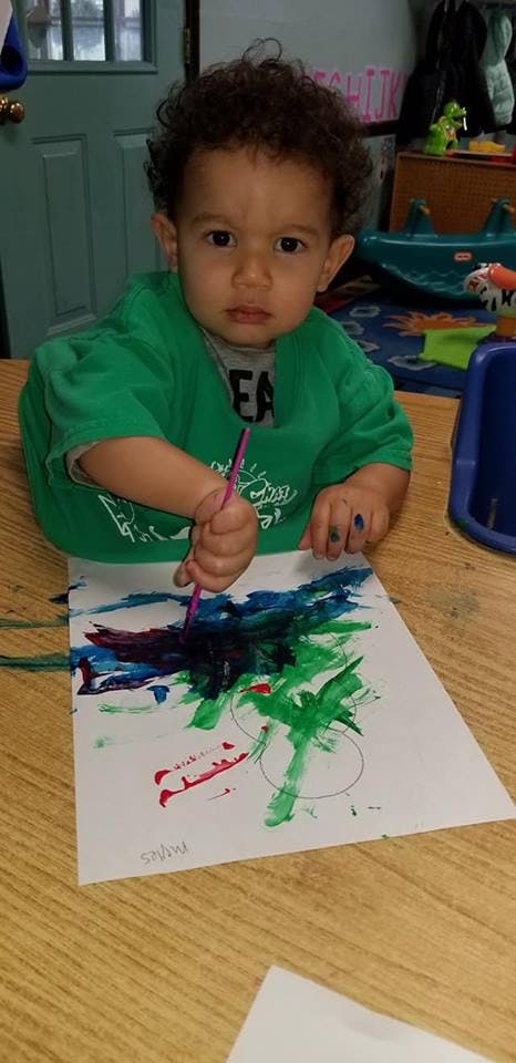 Child painting on paper with a brush
