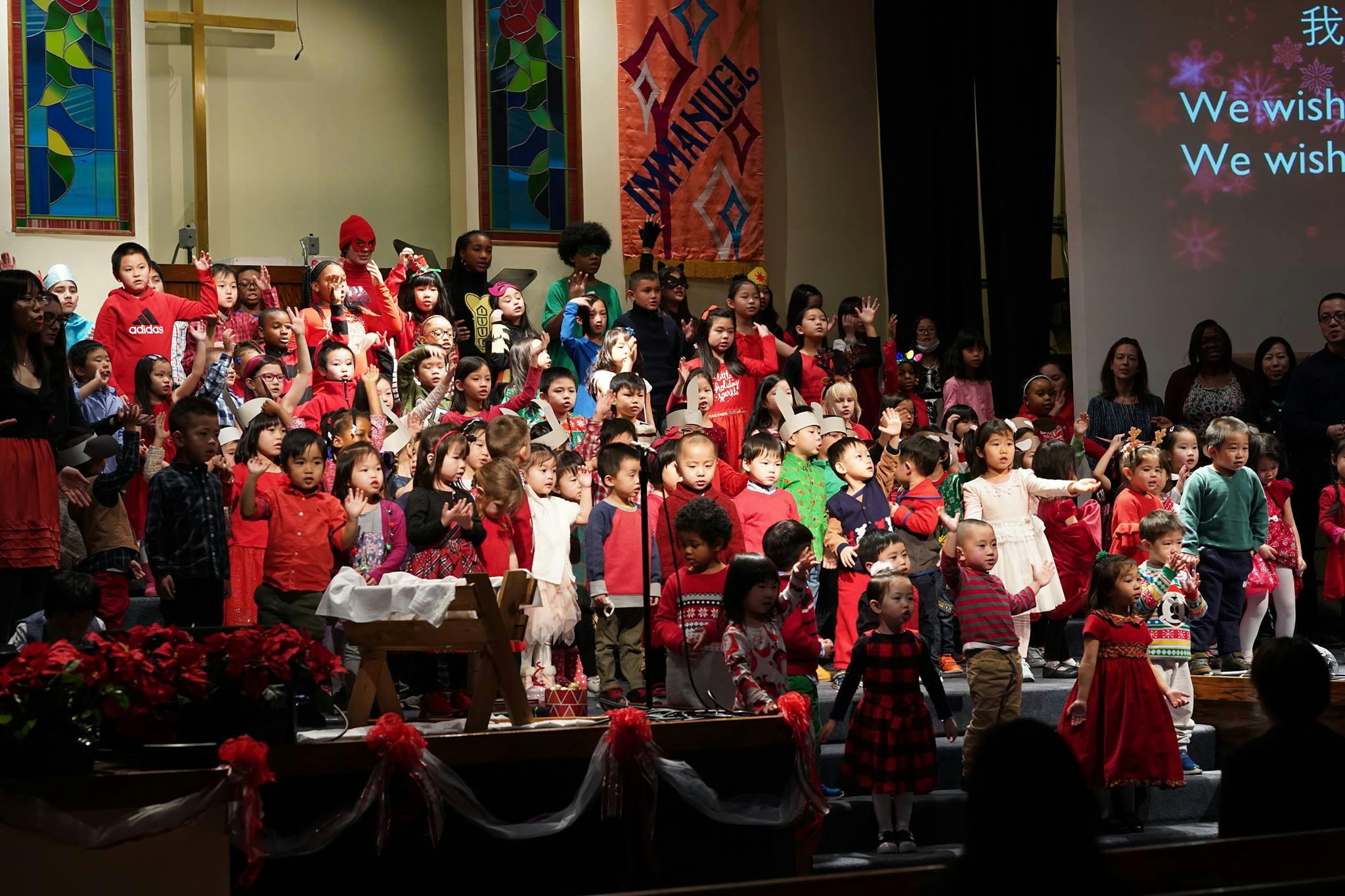 Large group of children on a stage, some raising hands