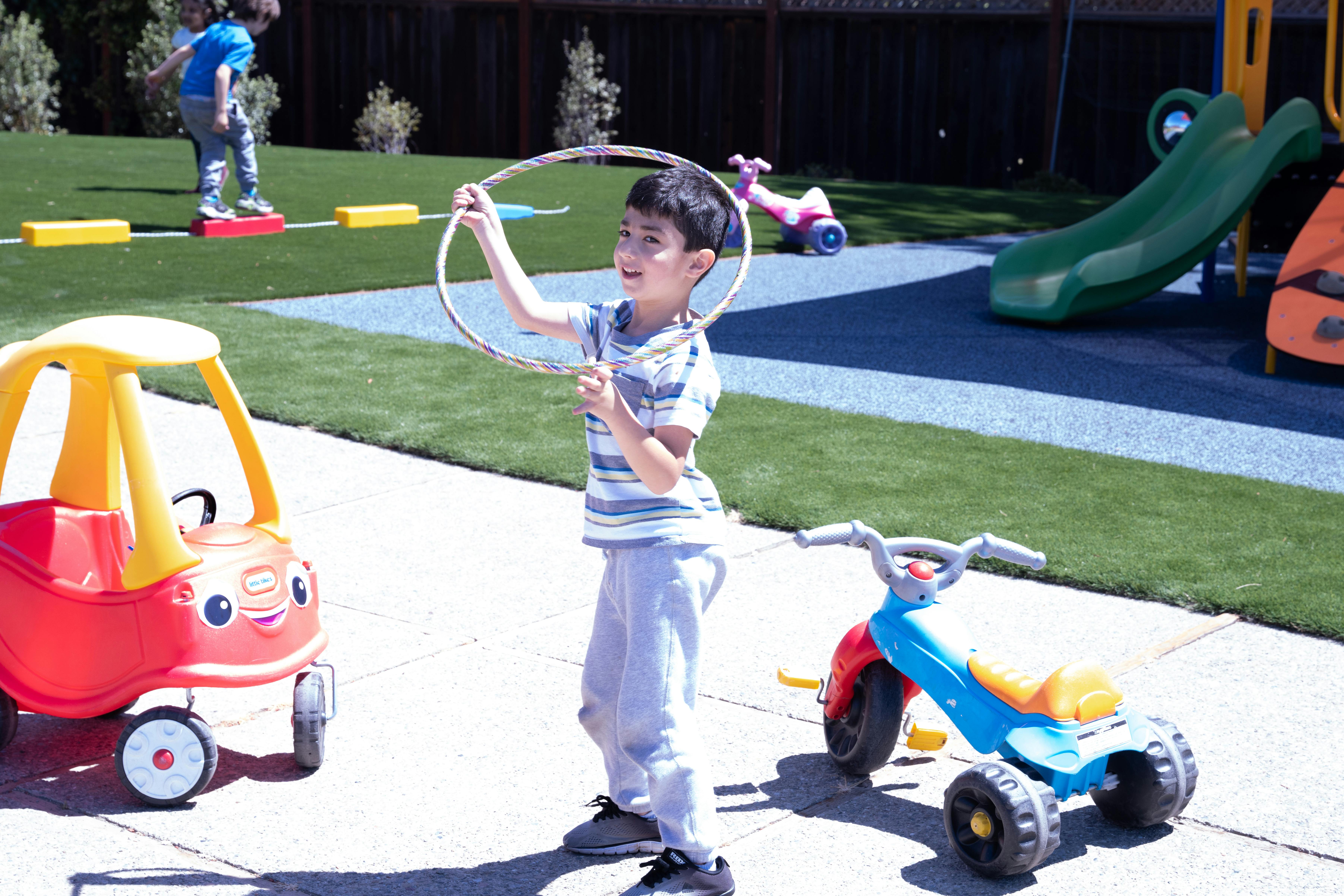 Child holding a hula hoop on a playground
