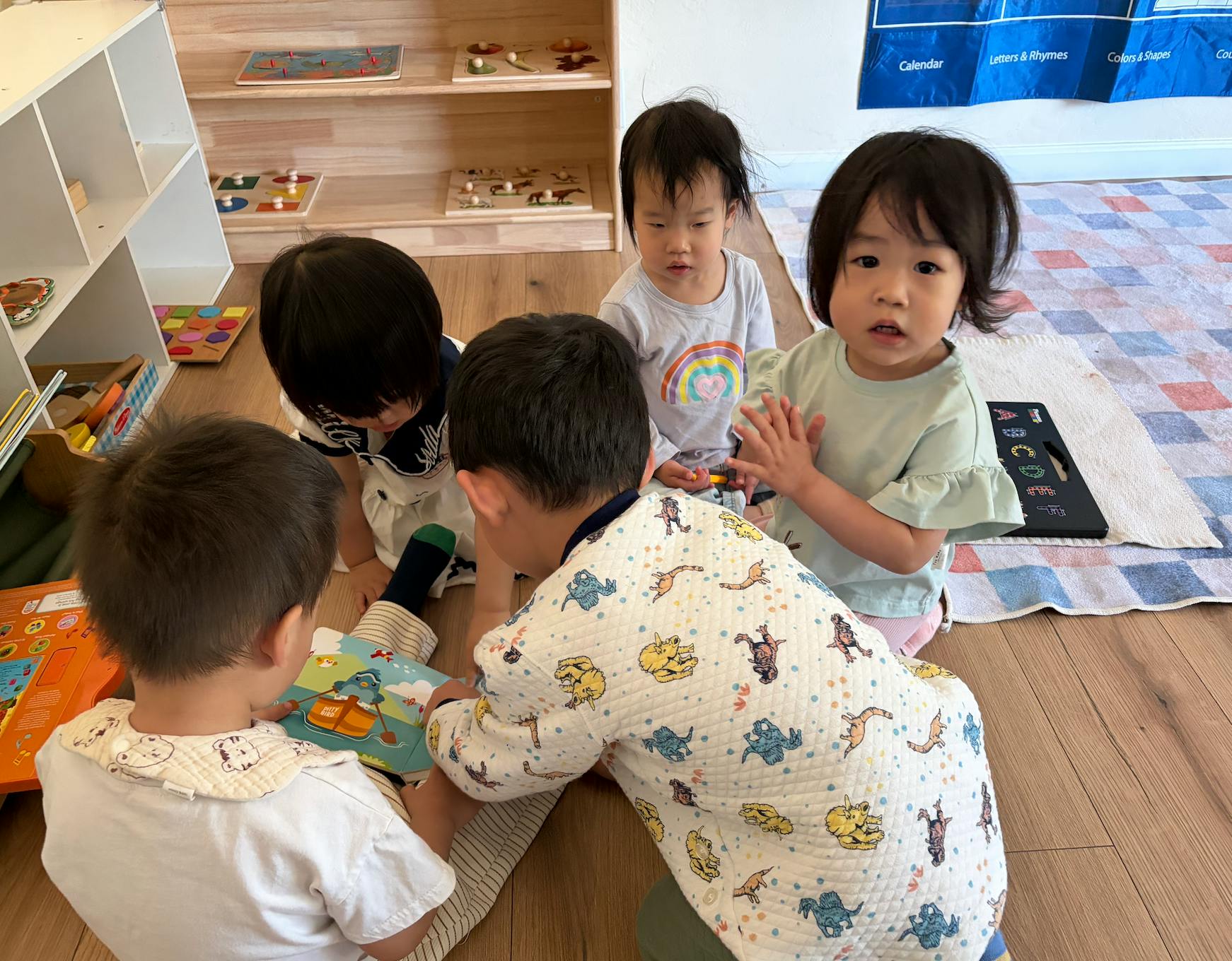 Four children sitting on the floor looking at a book