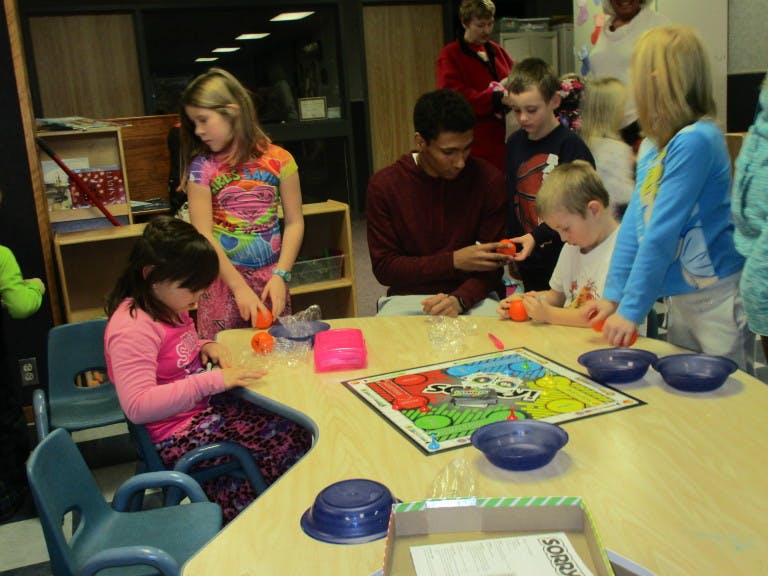 People and children playing a board game at a table
