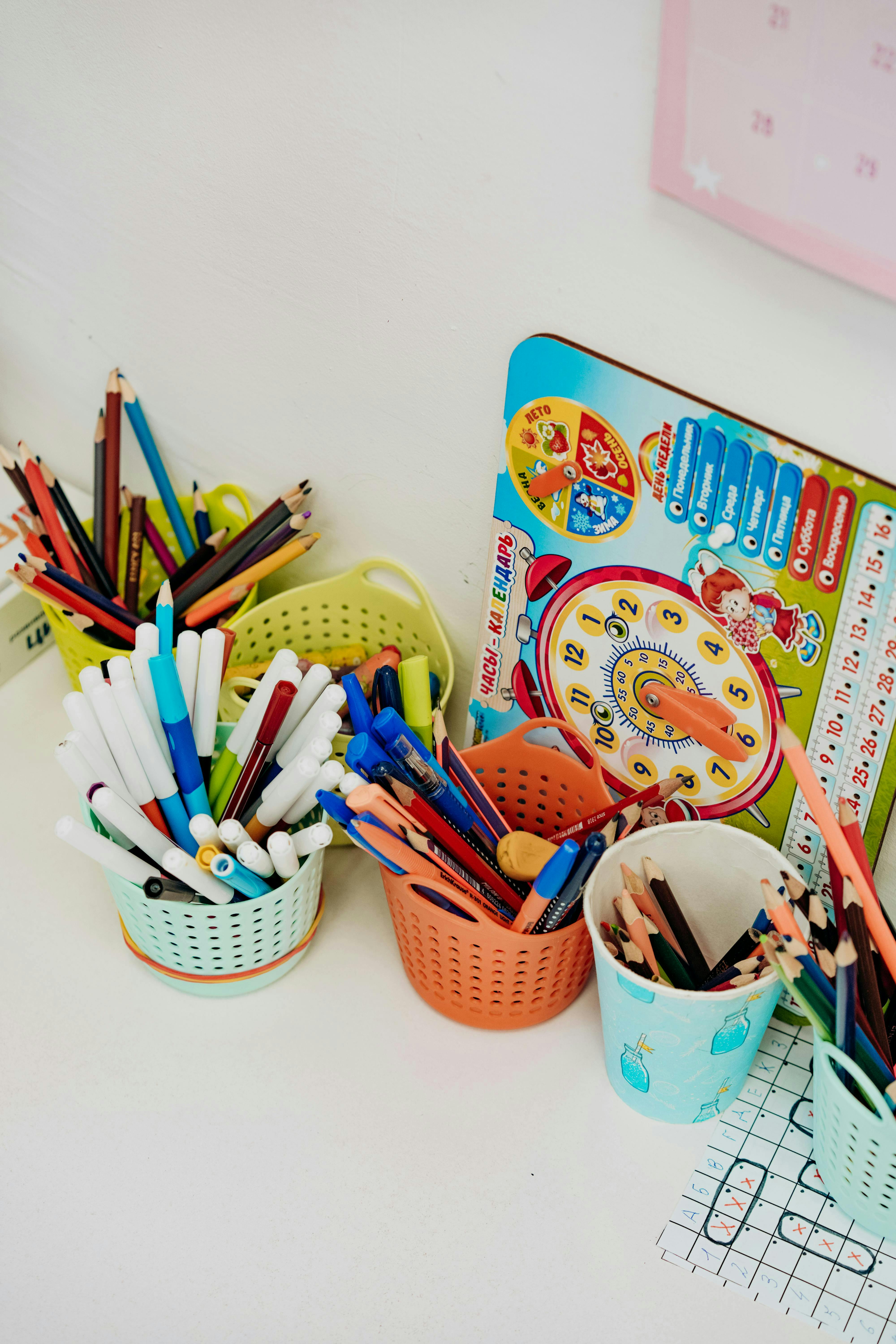 multiple containers filled with pencils, pens, and markers on a white surface