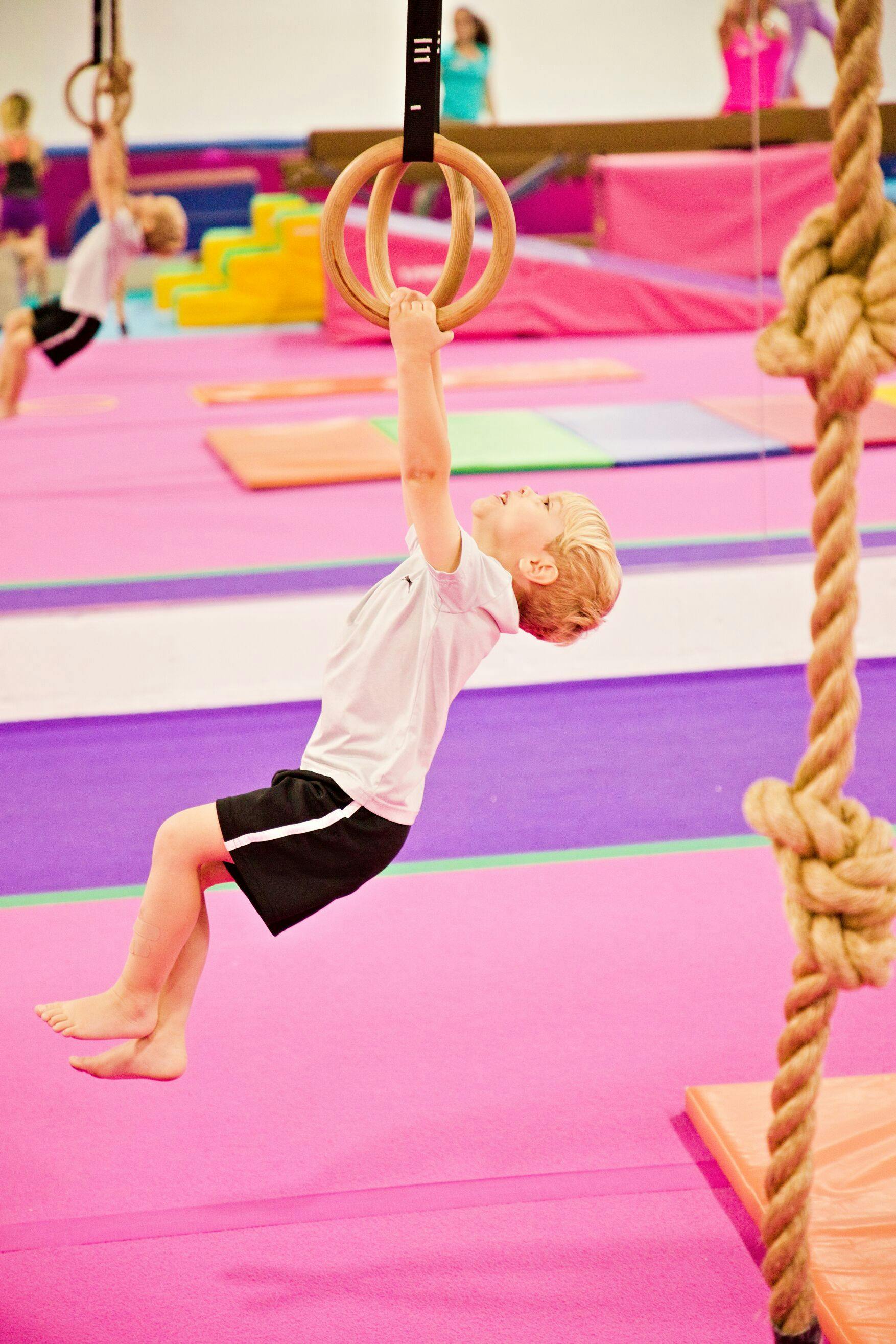 Child hanging from gymnastic rings in a gym