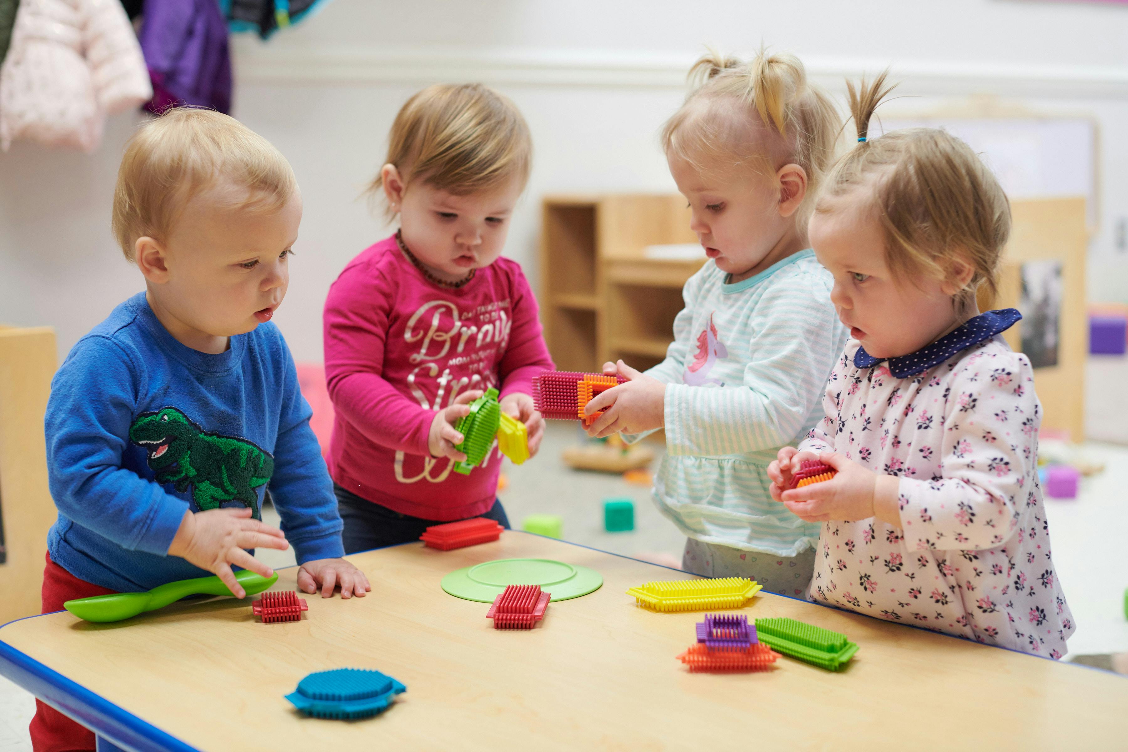 Four children playing with colorful blocks and toys at a table