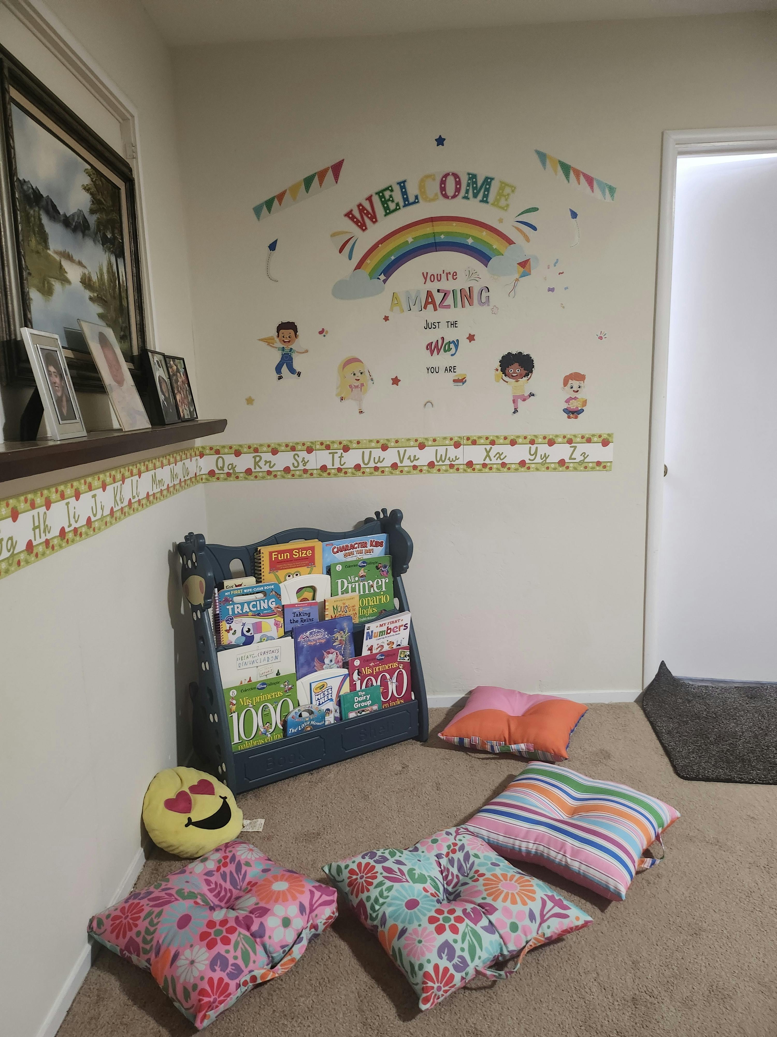 Children's reading nook with a bookshelf, floor cushions, and wall decals