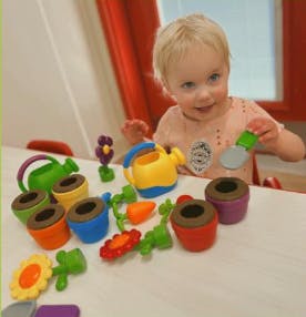 Child playing with toy gardening tools and pots