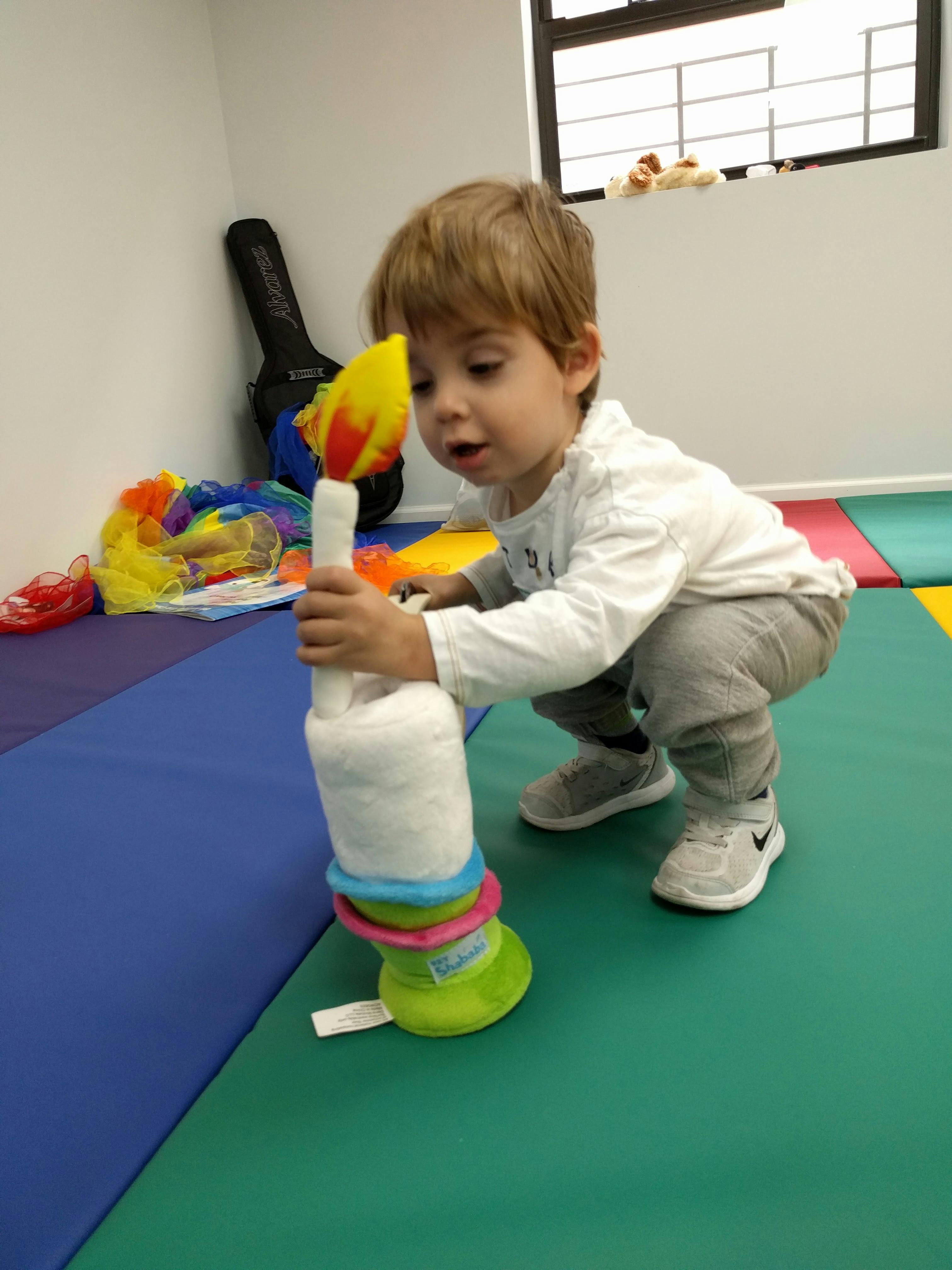 Child playing with a soft toy on a colorful mat