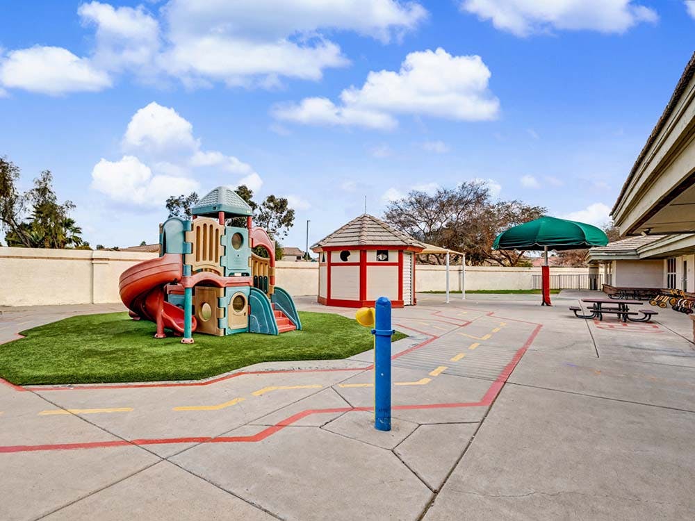 Colorful playground structure on artificial turf with a red and white playhouse