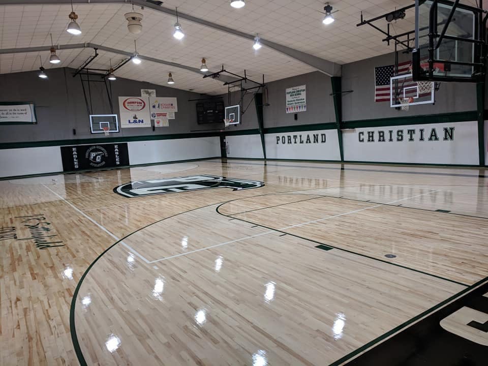 Empty basketball court with "Portland Christian" on the wall