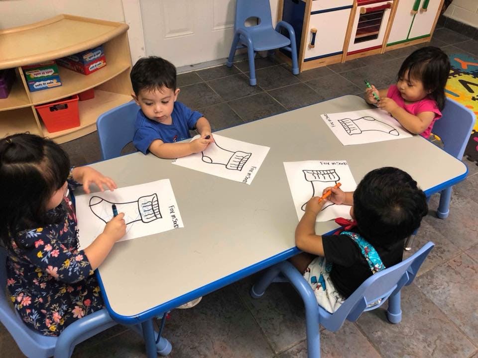 Four children coloring at a table in a classroom