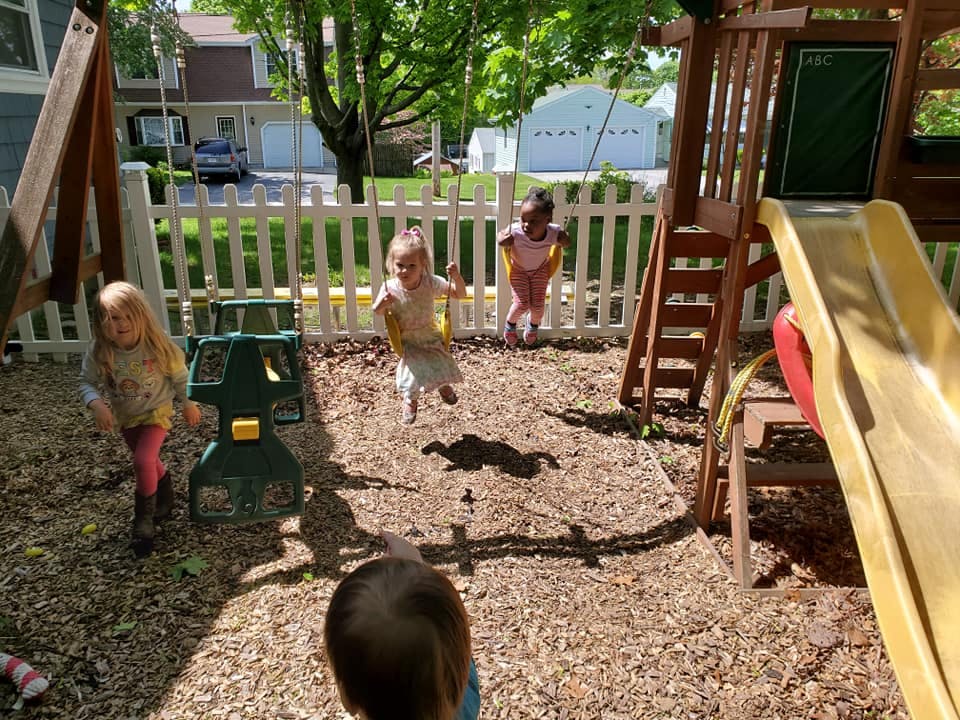 Children playing on a swing set and slide in a backyard