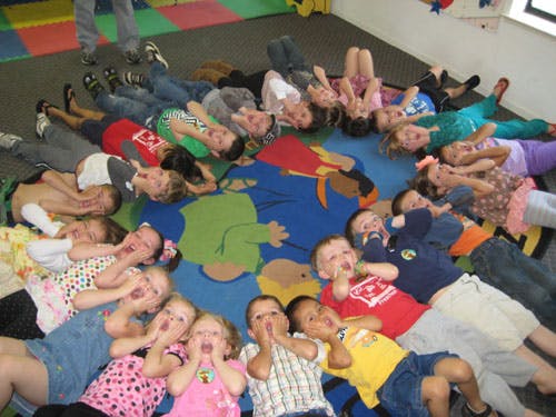 Group of children lying in a circle on a colorful rug