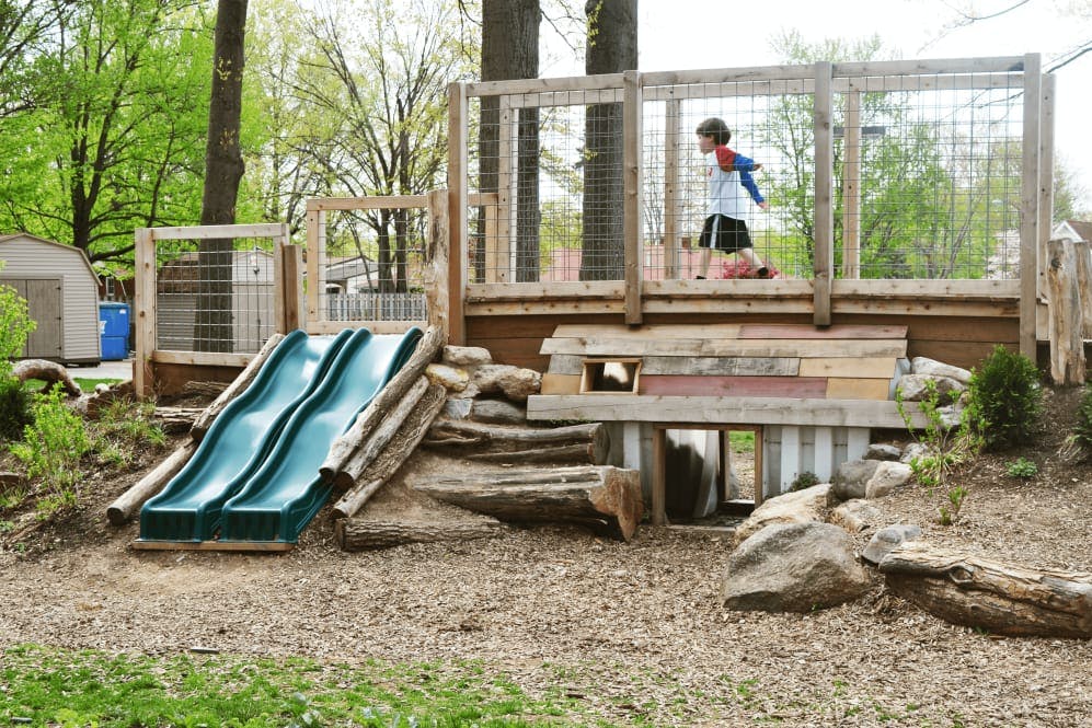 Child on a wooden playground structure with a slide