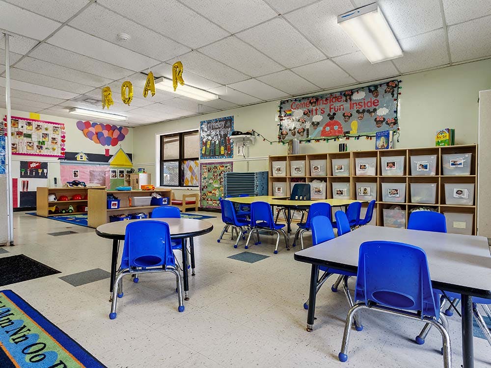 Classroom with small tables and chairs, shelves, and decorations