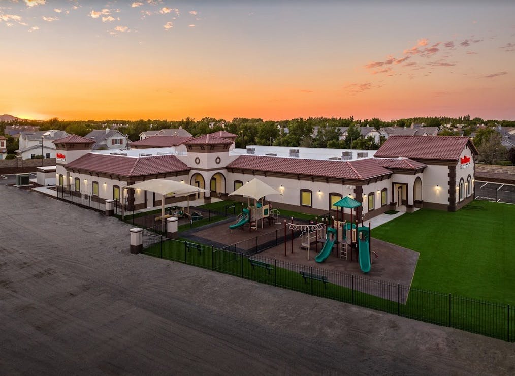 Building with playground and green lawn at sunset