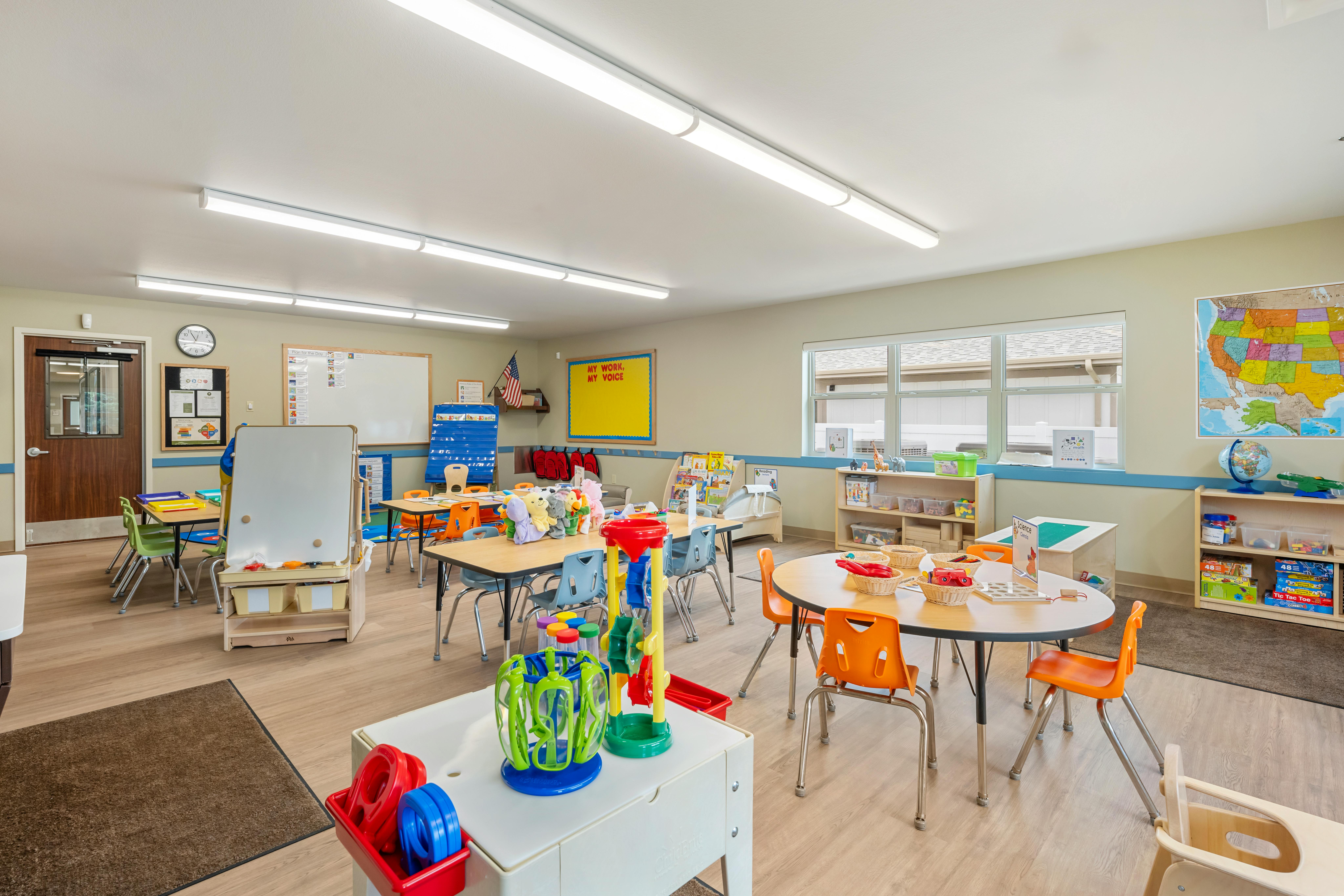 Classroom with child-sized tables and chairs, educational posters, and toys