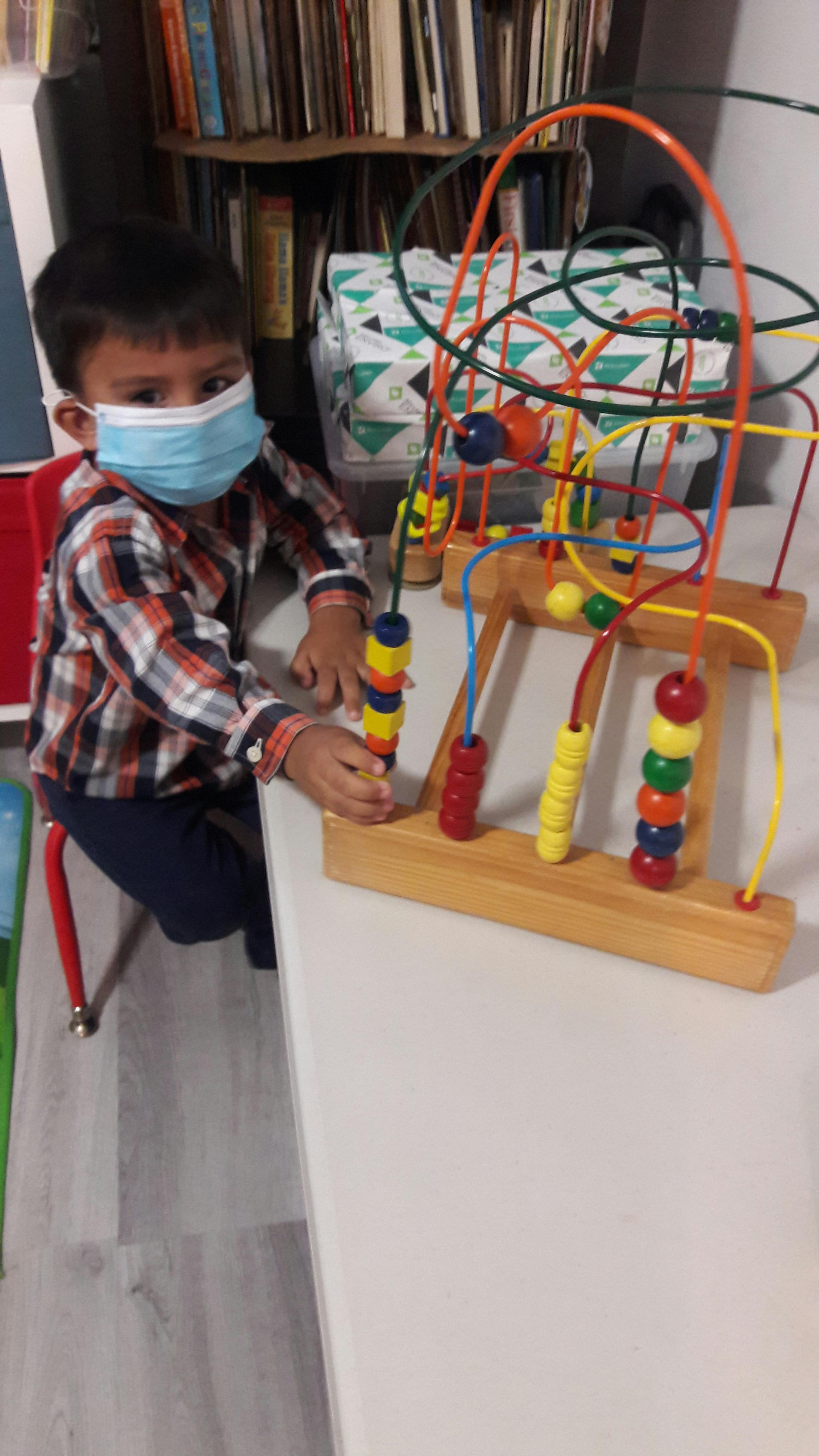Child in a face mask playing with a bead maze toy