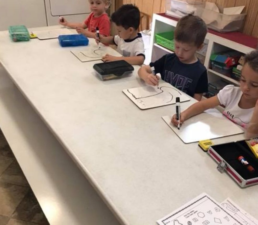 Children drawing on whiteboards at a table