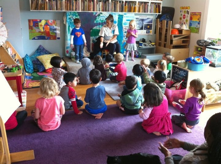 Adult and children sitting on floor in classroom