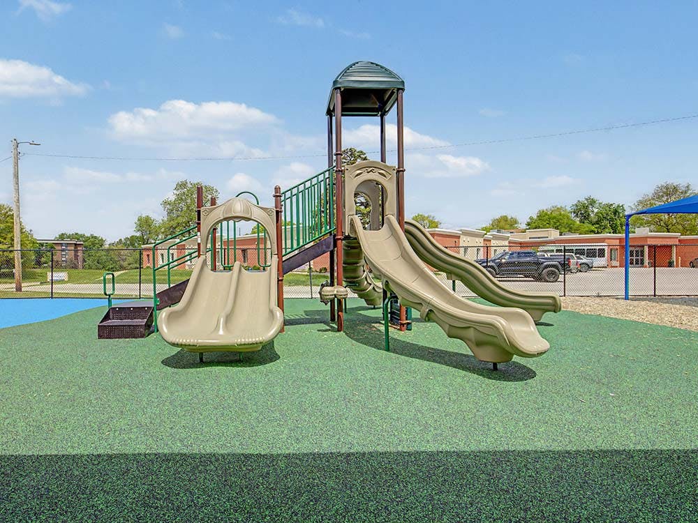 Playground structure with multiple slides on green safety surfacing